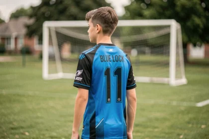 Adolescent de dos portant un maillot Blue Lock bleu et noir avec le numéro 11, sur un terrain de football